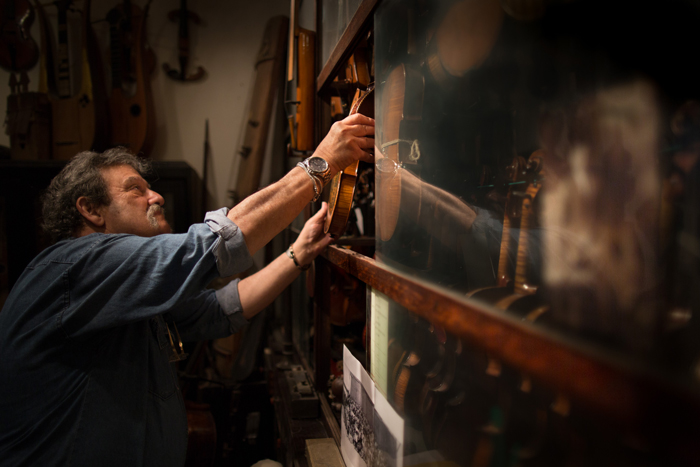 Amnon Weinstein returns a Holocaust violin to his glass-and-oak violin cabinet in his Tel Aviv workshop.