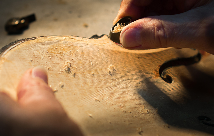 A detail of Amnon Weinstein’s process of removing fine shavings of wood from the rear of the front panel of a Holocaust violin.