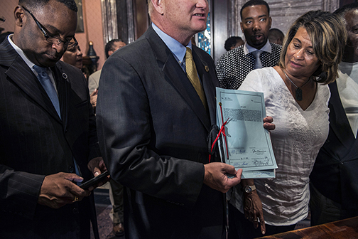 South Carolina’s Secretary of State Mark Hammond holding the bill signed by Governor Haley before handing it over to Wanda Williams-Bailey, the African-American granddaughter of segregationist Senator Strom Thurman, Columbia, SC (2015).