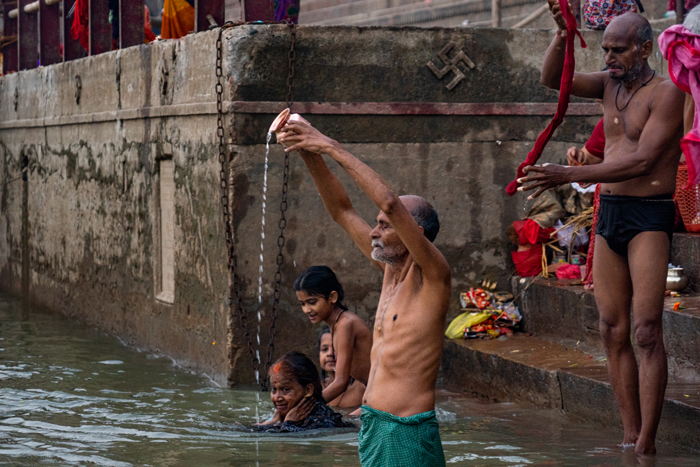 Devotees in the early morning, bathing and performing their observances to the Sun and Ganga.
