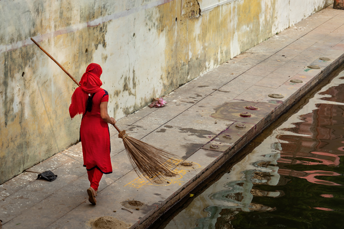A sweeper girl at the side of a kund, or pond.